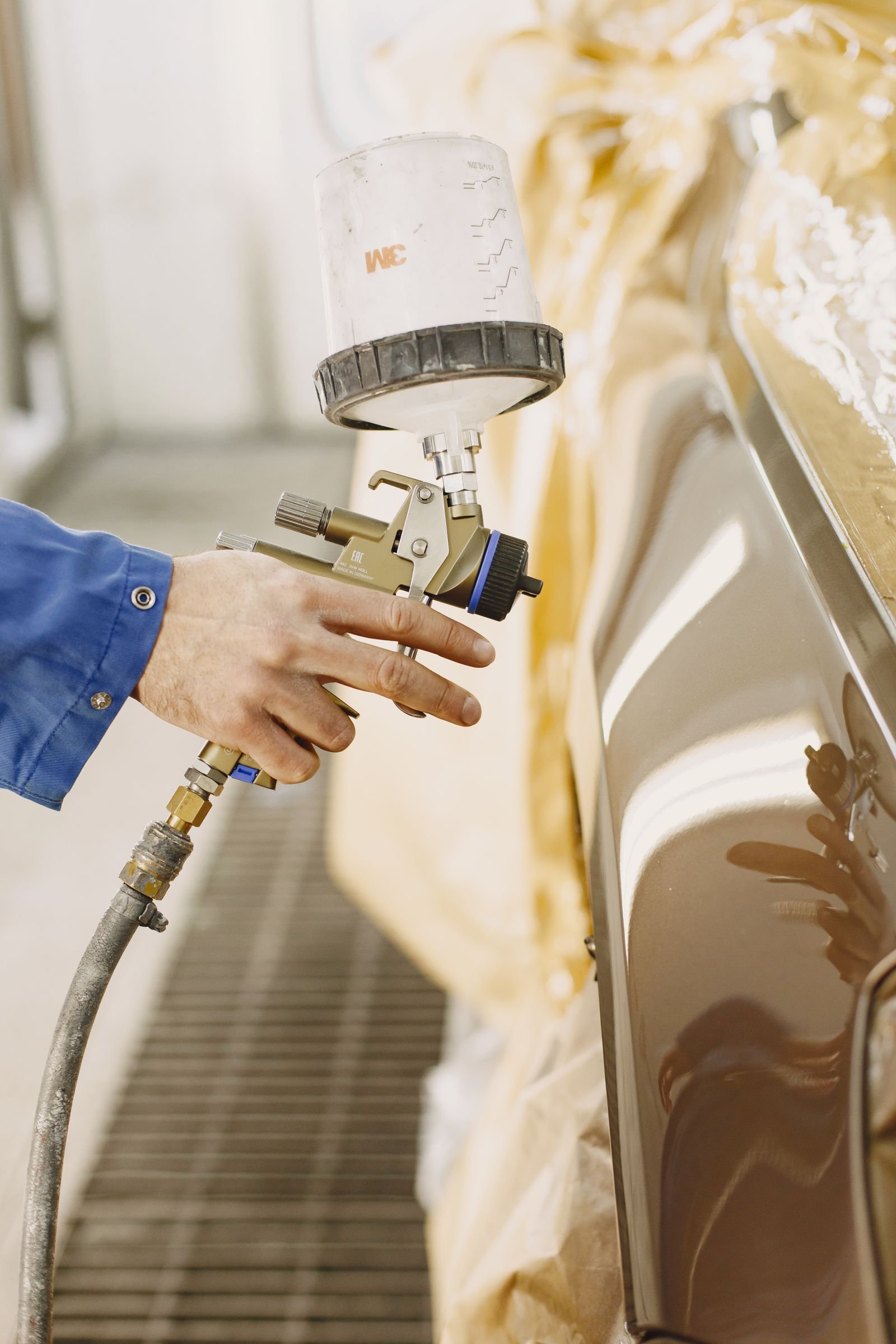 Technician spray-painting a commercial vehicle panel